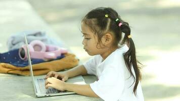fofa ásia menina usando computador portátil computador dentro a jardim. estilo de vida conceito. video