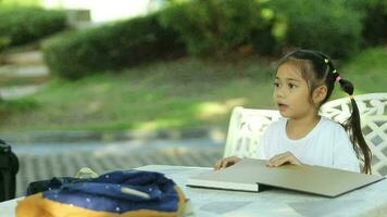 contento asiático niña leyendo libro en el jardín. educación concepto. video