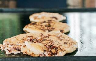 Traditional Nicaraguan pupusas with melted grilled cheese, Traditional cheese pupusas on the grill, Close up of traditional handmade pupusas on the grill. photo