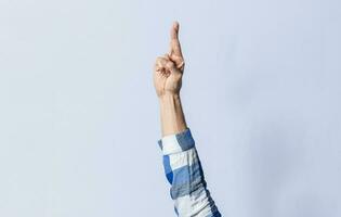 Hand gesturing the letter R in sign language on an isolated background. Man's hand gesturing the letter R of the alphabet isolated. Letter R of the alphabet in sign language photo
