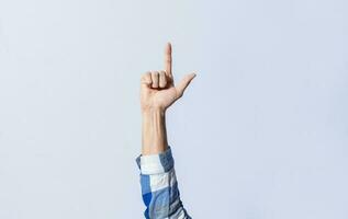 Hand gesturing the letter L in sign language on an isolated background. Man's hand gesturing the letter L of the alphabet isolated. Letters of the alphabet in sign language photo