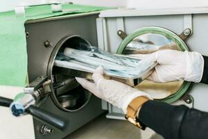 A dentist sterilizing his tools, Dentist with a dental sterilizer,  A dentist with a dental autoclave, Close up of a dentist with a steam sterilizer photo