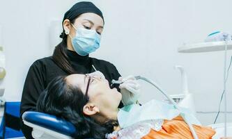 A dentist cleaning a patient's mouth, a dentist cleaning a patient's caries, a dentist cleaning a patient's mouth, The stomatologist cleaning a patient's teeth photo