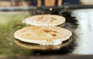 tradicional A la parrilla queso pupusas. cerca arriba de tradicional hecho a mano pupusas en parrilla, tradicional nicaragüense pupusas en parrilla foto