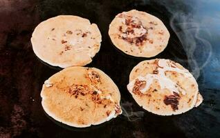 Traditional grilled cheese pupusas, Top view of four traditional handmade pupusas on grill. Traditional Salvadoran pupusas with melted cheese on a grill. photo