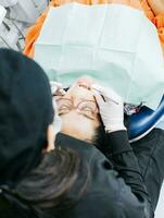 View back of dentist with patient lying down. Female dentist doing endodontics to woman patient. Dentist examining mouth to patient. Dentist performing stomatology photo