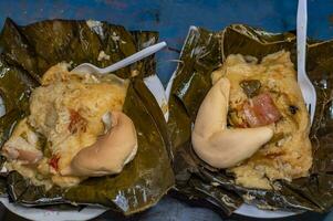 Two Nacatamales served in a banana leaf on the table. Top view of two traditional Nacatamales served on banana leaf, Two Nacatamales with bread served on the table, Venezuelan Hallaca served photo