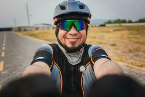 Self portrait of happy male cyclist outdoors. Happy Cyclist with glasses and helmet taking a selfie photo