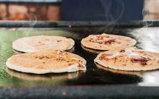 tradicional A la parrilla queso pupusas, cerca arriba de cuatro tradicional hecho a mano pupusas en el parrilla. tradicional nicaragüense pupusas con Derretido queso en un parrilla foto