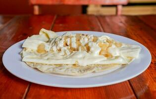 Plate of delicious Quesillo with pickled onion served on the table, Traditional quesillo plate with pickled onion and cream. Concept of typical Nicaraguan foods photo