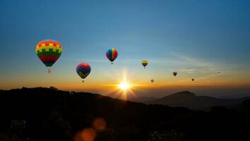 Colorful hot air balloons flying above mountain at sunrise sky background. Travel natural background. photo