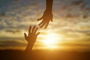 silueta de alcanzando, dando un Ayudar mano, esperanza y apoyo cada otro terminado puesta de sol antecedentes. ayuda concepto foto