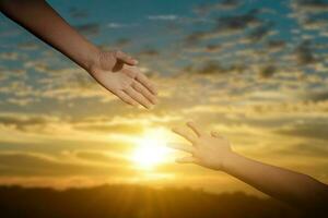 Giving a help hand concept. Reaching hand helping, hope and support each other over sunset background. photo