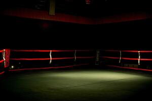 un vacío boxeo anillo iluminado arriba a noche. ai generado foto