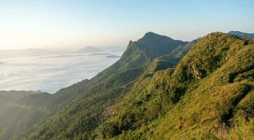 Beautiful landscape on the mountains at sunrise. Spectacular view in foggy valley covered forest under morning time. photo