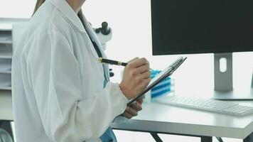 Health care researchers working in life science laboratory. Young female research scientist and senior male supervisor preparing and analyzing microscope slides in research lab. video