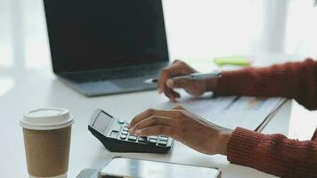 Charming Young asian businesswoman sitting on laptop computer in the office, making report calculating balance Internal Revenue Service checking document. video