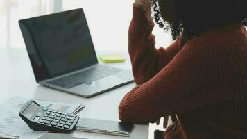 encantadora joven mujer de negocios asiática sentada en una computadora portátil en la oficina, haciendo un informe que calcula el documento de verificación del servicio de ingresos internos del saldo. video