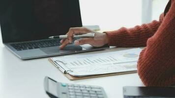 Charming Young asian businesswoman sitting on laptop computer in the office, making report calculating balance Internal Revenue Service checking document. video