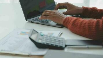 Charming Young asian businesswoman sitting on laptop computer in the office, making report calculating balance Internal Revenue Service checking document. video