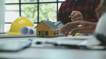 équipe de Multi-éthnique architectes travail sur construction des plans dans réunion chambre. ingénieurs discuter sur projet dans bureau. mature homme d'affaire et femme permanent autour table travail sur plan. video