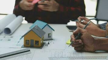 équipe de Multi-éthnique architectes travail sur construction des plans dans réunion chambre. ingénieurs discuter sur projet dans bureau. mature homme d'affaire et femme permanent autour table travail sur plan. video