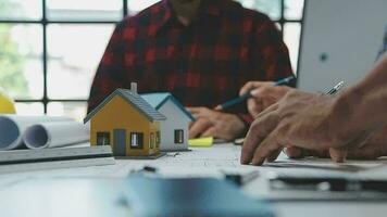 équipe de Multi-éthnique architectes travail sur construction des plans dans réunion chambre. ingénieurs discuter sur projet dans bureau. mature homme d'affaire et femme permanent autour table travail sur plan. video