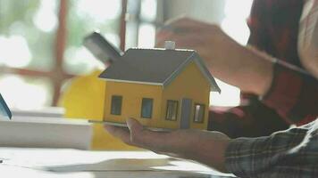 équipe de Multi-éthnique architectes travail sur construction des plans dans réunion chambre. ingénieurs discuter sur projet dans bureau. mature homme d'affaire et femme permanent autour table travail sur plan. video