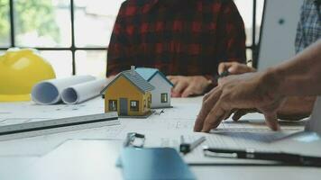 équipe de Multi-éthnique architectes travail sur construction des plans dans réunion chambre. ingénieurs discuter sur projet dans bureau. mature homme d'affaire et femme permanent autour table travail sur plan. video