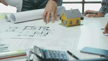 équipe de Multi-éthnique architectes travail sur construction des plans dans réunion chambre. ingénieurs discuter sur projet dans bureau. mature homme d'affaire et femme permanent autour table travail sur plan. video