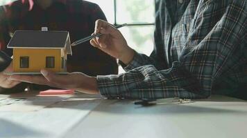 équipe de Multi-éthnique architectes travail sur construction des plans dans réunion chambre. ingénieurs discuter sur projet dans bureau. mature homme d'affaire et femme permanent autour table travail sur plan. video