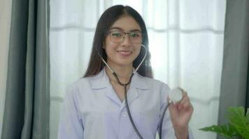 asiático mujer médico en pie con estetoscopio en examen habitación a el clínica. video