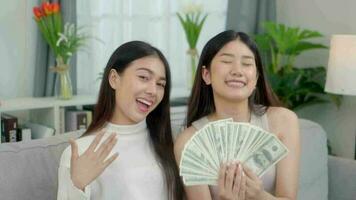 Happy two Asian young women are showing dollars and showing thumbs up. Online business success consept. video