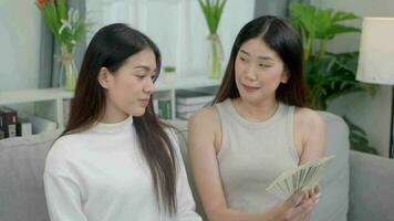 glücklich zwei asiatisch jung Frauen sind zeigen Dollar und zeigen Daumen hoch. online Geschäft Erfolg Konzept. video