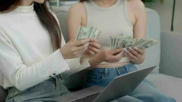 Two asian girls counting money dollars at home.  Online business success consept. video