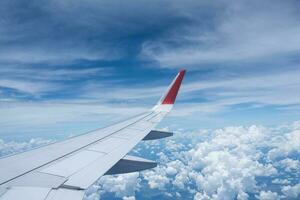 Airplane wing flying above the sky with white clouds. View from aircraft window. flying and traveling concept. photo