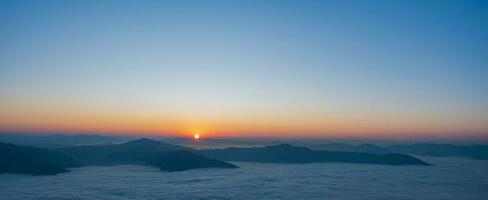 Beautiful landscape on the mountains at sunrise. Spectacular view in foggy valley covered forest under morning sky. Panorama Picture photo