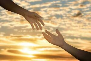 Giving a help hand concept. Reaching hand helping, hope and support each other over sunset background. photo