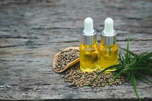 Hemp seeds and hemp oil on wooden table. Hemp seeds in wooden spoon and hemp essential oil in small glass bottle. cannabis oil cbd. photo