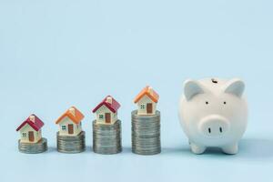 mini casa en apilar de monedas en un azul antecedentes. concepto de inversión propiedad, real bienes, ahorro dinero. foto