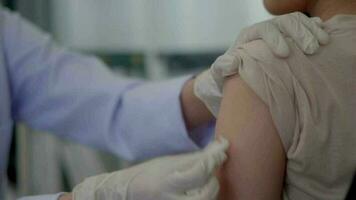 dichtbij omhoog hand- Aziatisch vrouw dokter injecteren in arm van Aziatisch meisje. video
