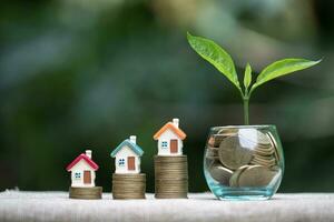 House model and step of coins stacks with coins in glass jar and growing tree on top,  money, saving and Real estate investment or family planning concept. photo