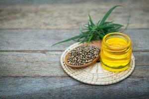 Glass bottles containing  hemp oil and hemp seeds in a wooden spoon,  drugs extracted CBD Cannabis Oil  of researchers or medical team. Herbal alternative medicine. photo