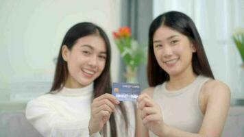 Due asiatico sorridente donne nel mostrando credito carta. in linea successo acquistare saldi. video