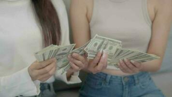 vicino su mano Due asiatico ragazze conteggio i soldi dollari a casa. in linea attività commerciale successo concetto. video