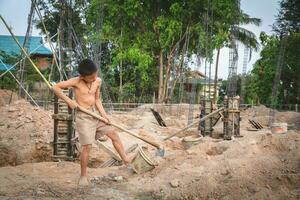 chico obrero en un construcción sitio forzado mano de obra. en contra niño mano de obra, pobre niños, construcción trabajar, violento niños y humano tráfico foto