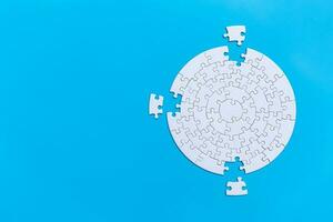 Unfinished white jigsaw puzzle pieces on blue background,  Copy space. photo