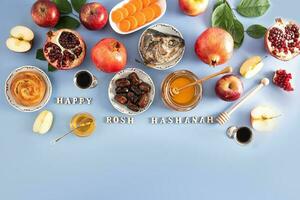 festivo antecedentes para rosh hashaná. un conjunto de tradicional comida en un azul antecedentes con y de madera letras con el texto de Felicidades. foto