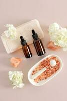A set of cosmetics in bottles with a pipette, a white roller and bath salts on a pastel background. The concept of self-care. spa. Top vertical view. photo