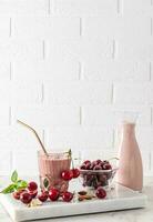 Beautiful vertical look of a still life with a delicious healthy cherry smoothie in a bottle and glass with eco-friendly straw. ripe berries. photo